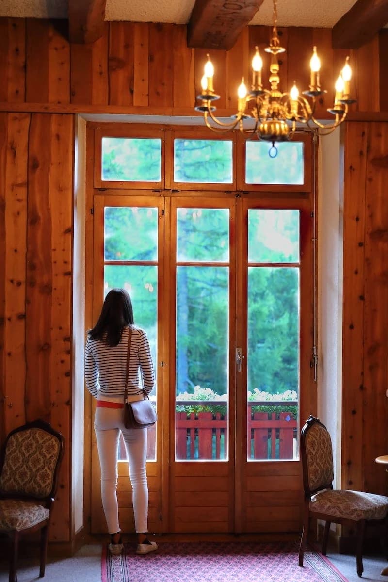 Hôte contemplant la forêt d'arolles depuis le salon historique